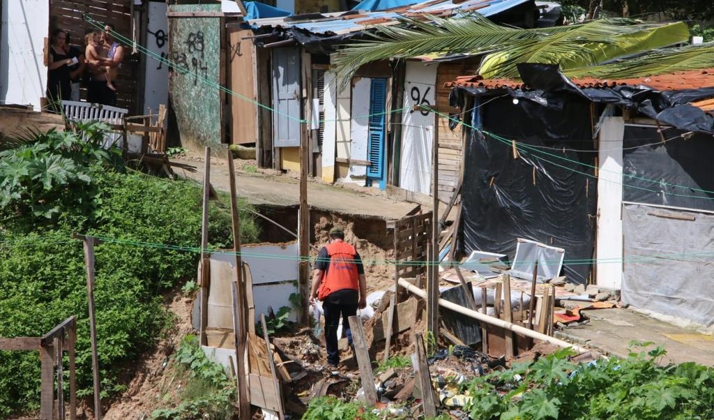 agente da defesa civil caminha na frente dos barracos localizados em área de risco